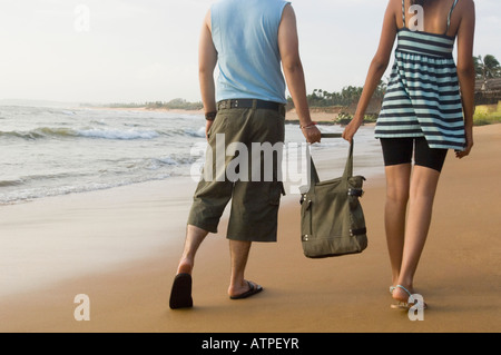 Rückansicht eines jungen Paares hält eine Tasche und Wandern am Strand Stockfoto