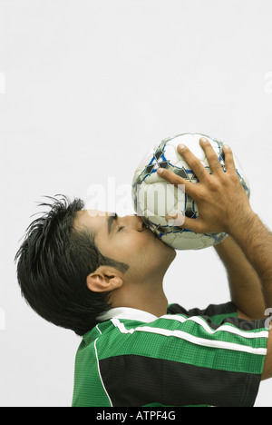 Nahaufnahme eines jungen Mannes küssen einen Fußball Stockfoto