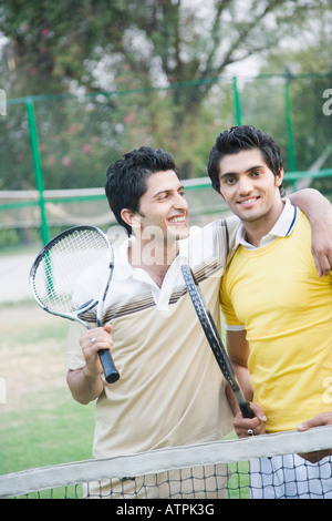 Zwei junge Männer Tennisschläger in einem Gericht halten und Lächeln Stockfoto