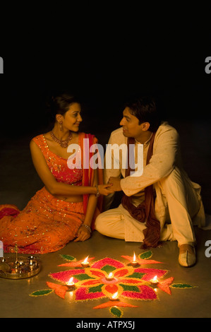 Junges Paar sitzt mit Hand in Hand vor rangoli Stockfoto