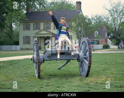 Ein junger Besucher spielt auf eine alte Kanone in den wichtigsten Platz der alten Colonial Williamsburg Stockfoto