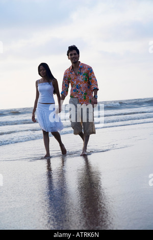 Porträt eines jungen Mannes Hand in Hand einer jungen Frau und zu Fuß am Strand Stockfoto