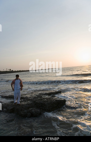 Junger Mann stehend auf einem Felsen im Meer Stockfoto