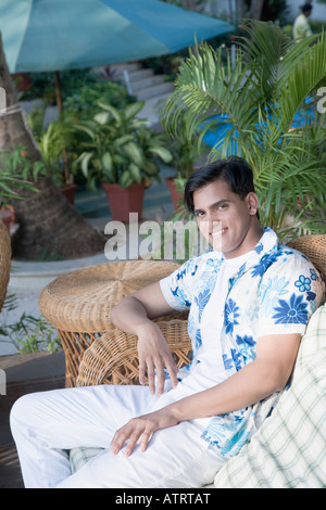 Porträt eines jungen Mannes auf einer Couch sitzen und Lächeln Stockfoto