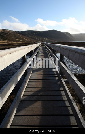 hölzerne Fußgängerbrücke über den Fluss in Richtung Hügel in Glen Muick in der Nähe von Ballater, Aberdeenshire, Schottland, UK Stockfoto