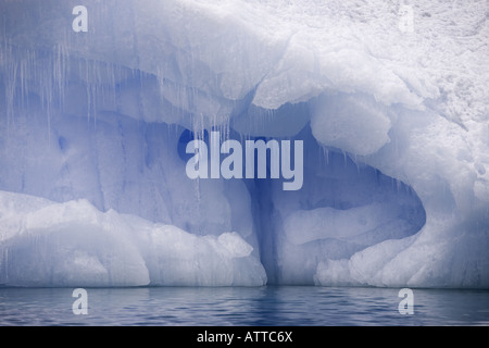 Schnee bedeckten blauen Eisberg mit Eishöhle im Inneren und Eiszapfen hängen in der Antarktis Stockfoto