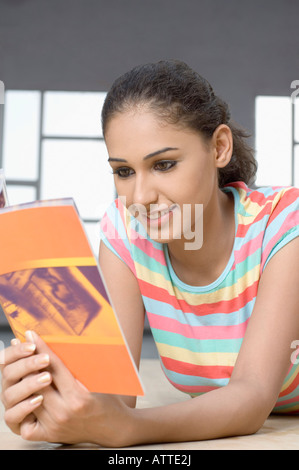 Nahaufnahme einer jungen Frau auf dem Parkett liegen und Lesen einer Zeitschrift Stockfoto
