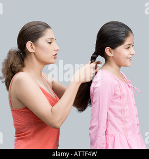 Seitenansicht einer jungen Frau, die ihre Tochter Haare flechten Stockfoto