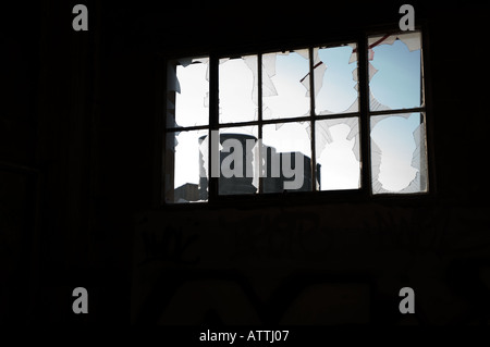 Zerbrochenes Fensterscheiben Hintergrundbeleuchtung durch späten Abend Sonne in einer alten verlassenen Zementfabrik in Shoreham East Sussex Stockfoto