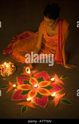 Erhöhte Ansicht einer jungen Frau, die Verzierung Rangoli mit Öllampen Stockfoto