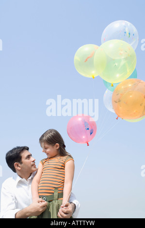Niedrigen Winkel Blick auf einem Mitte erwachsenen Mann mit seiner Tochter mit Luftballons Stockfoto