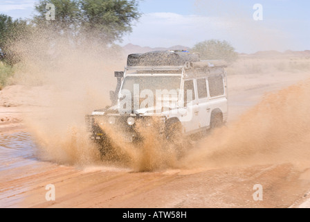 Land Rover Strahlen durch stehendes Wasser in der namibischen Wüste in Namibia Stockfoto