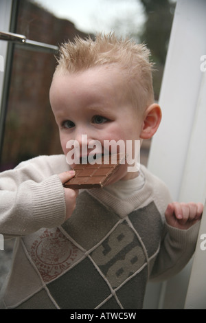 Ein Kleinkind Essen eine große Tafel Milchschokolade Stockfoto