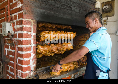 Mexiko Guanajuato junge männliche setzen ganze Hähnchen am Drehspieß Holz gefeuert Steinofen viele Geflügel auf rotierende Spieße Stockfoto