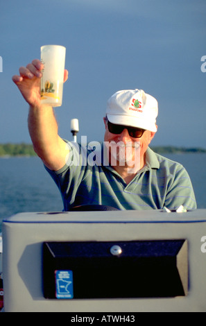 Mann Alter 55 holding up trinken während der Fahrt Motorboot. Clitherall Minnesota USA Stockfoto