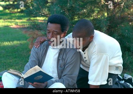 Schwarzen Großvater Alter von 70 Jahren und Enkel Alter 13 lesen Bibel im Park. St Paul Minnesota USA Stockfoto