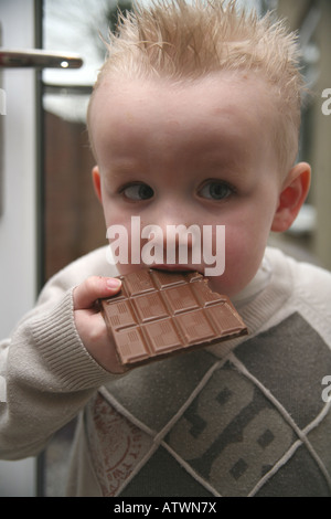 Ein Kleinkind Essen eine große Tafel Milchschokolade Stockfoto