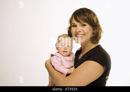 Eine schöne junge Mutter hält ihre Tochter im Studio. Stockfoto