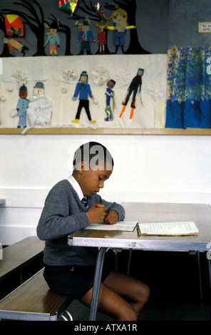 Junges Kind arbeitet an seinem Schreibtisch in einem South London Grundschule Klassenzimmer Stockfoto