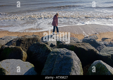 Frinton am Strand bei Ebbe mit Frau Walker und den Felsen zum Schutz vor Erosion vor Stockfoto