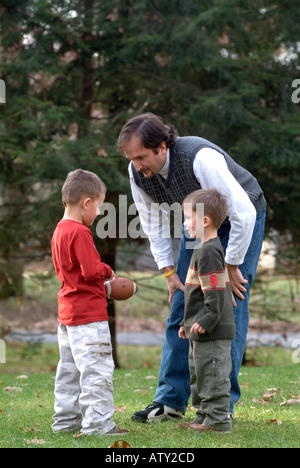 Männliche Mitglieder einer Großfamilie spielen Fußball in ihrem Vorgarten am Thanksgiving day Stockfoto