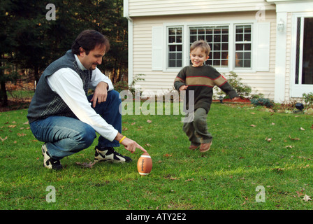 Männliche Mitglieder einer Großfamilie spielen Fußball in ihrem Vorgarten am Thanksgiving day Stockfoto