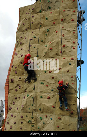 Junge Kinder einige Klettern Praxis auf einer künstlichen Felswand. Stockfoto
