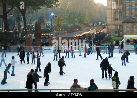 Erwachsene & Kinder auf Schlittschuhen an temporären Weihnachten Eisbahn am Natural History Museum in South Kensington West London England Großbritannien Stockfoto