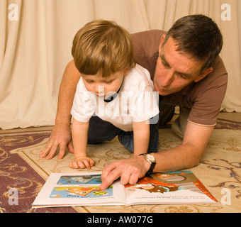 Großvater-Vater-Lesung am Boden mit Enkel Sohn zwei Jahre alt Stockfoto