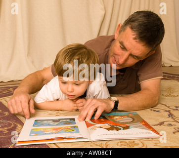 Großvater liest auf dem Boden mit Sohn Enkel zwei Jahre alt Stockfoto