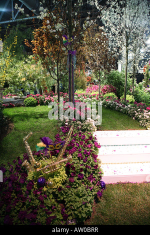 Weiße Schritte verstreut mit Glitzer und eingefasst mit glitzernden Perlen. Grasbewachsenen Weg eingefasst mit rosa und weiß blühenden Pflanzen. Stockfoto