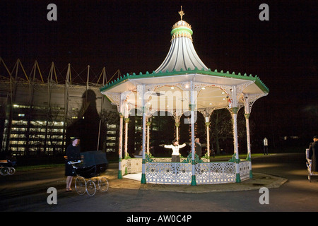 UK Tyneside Newcastle upon Tyne Winter Festival Leazes Park Enchanted Parks Skater im Musikpavillon mit Kindermädchen zu Fuß Kinderwagen Stockfoto