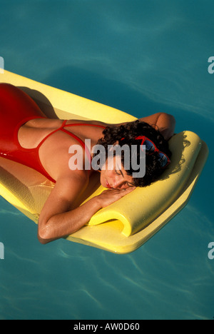 Frau schwimmt auf Floß im Schwimmbad Stockfoto