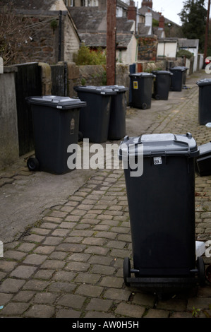 schwarzen Rädern Wheelie bin Mülleimer in einer Seitengasse Ginnel hinter einer Reihe von Reihenhäusern in eine Stadt in Nord england Stockfoto