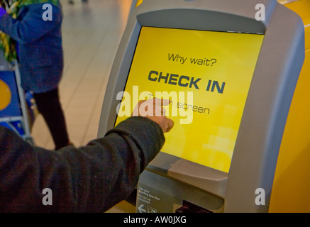 Frau mit dem Selbsttest im Terminal mit sensiblen Touchscreen auf Shiphol Airport, Niederlande Stockfoto