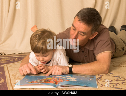 Großvater liest auf dem Boden mit Sohn Enkel zwei Jahre alt Stockfoto