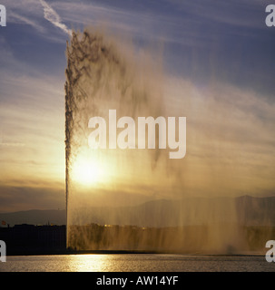 Auf der Suche über die ruhige Oberfläche des Genfer Sees bei Sonnenuntergang zum mächtigen Wasserbrunnen bei Genf Schweiz Stockfoto