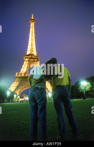 Rückansicht der paar Umarmung in der Nähe von Eiffelturm bei Nacht Stockfoto
