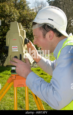 Mann tragen Schutzhelm Vermessung Grundstücke zum Neubau mit automatische Entfernung Messgerät Stockfoto