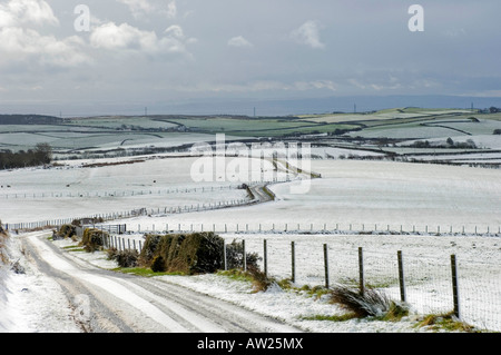 Eine Schnee bedeckten Moor Straße an einem schottischen Wintermorgen führt hinunter zu den Firth of Clyde. Stockfoto