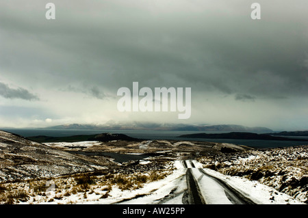 Eine Schnee bedeckten Moor Straße an einem schottischen Wintermorgen führt hinunter zu den Firth of Clyde. Stockfoto