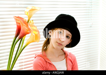 Indoor-Porträt der jungen Pre Teen Teenager-Mädchen in schwarzen Hut in der Nähe von Fenster mit Blumen Stockfoto