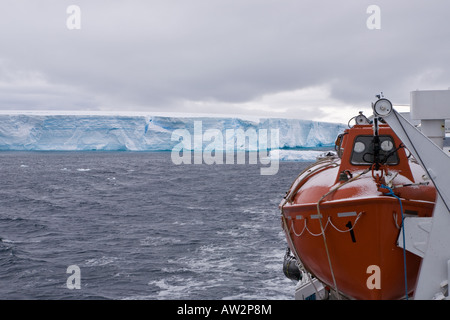 Nahaufnahme von Rettungsboot auf Schiff, vorbei an riesigen tabellarischen Eisbergs im Hintergrund Stockfoto