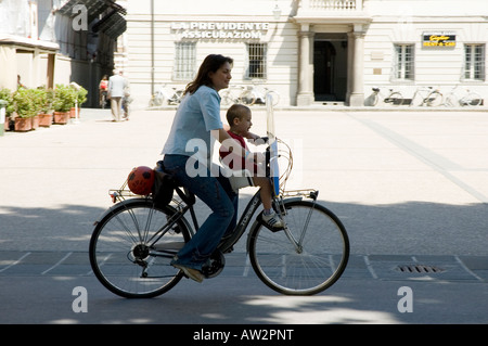 Italienische Frau Reiten Fahrrad mit Kind im Sitz Stockfoto