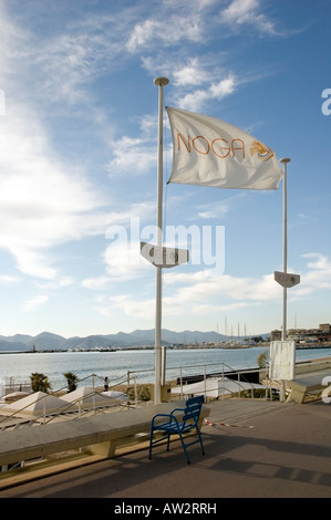 NOGA, Restaurant Strandaufgang und leeren blauen Stuhl in der Wintersonne auf Promenade La Croisette, Cannes, Côte d ' Azur, EU Stockfoto