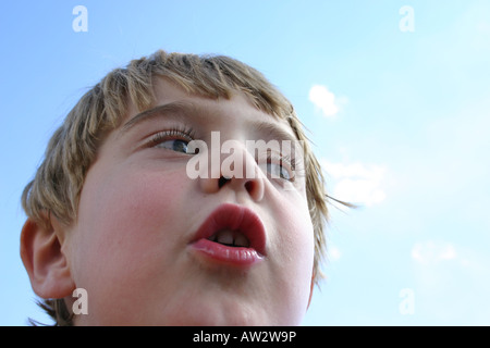 sprechen Sie sieben Jahre alter Junge mit dem Ausdruck selbst im Freien mit blauem Himmelshintergrund, Kommunikation, Kindheit, Sprache Stockfoto