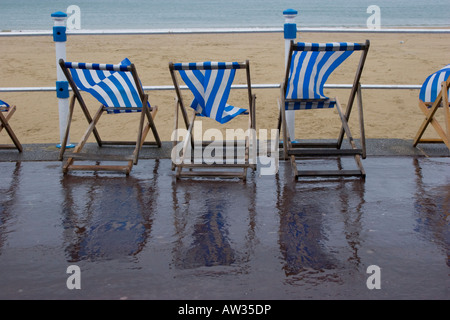 Liegestühle am Strand bei schlechtem nassem Wetter in Weymouth, Dorset Stockfoto