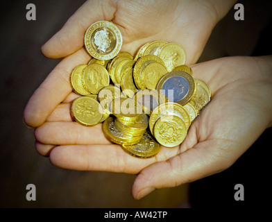 Eine englische Pfund-Münzen und zwei Pfund-Münzen in der hohlen Hand Stockfoto