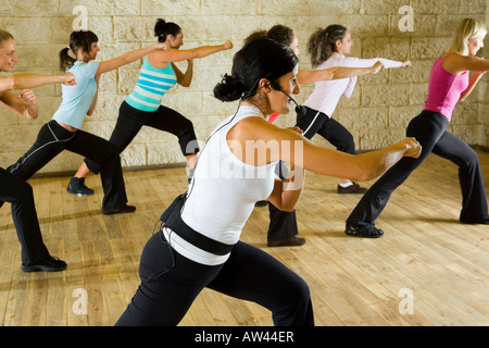 Eine Gruppe von Frauen, die das Training mit Fitness-Trainer in der Turnhalle Fokus auf die Frau in weißem Hemd Seitenansicht Stockfoto