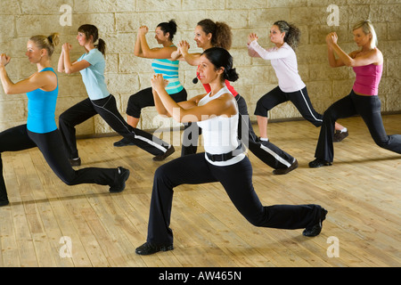 Eine Gruppe von Frauen, die das Training mit Fitness-Trainer in der Turnhalle Fokus auf die Frau in weißem Hemd Seitenansicht Stockfoto